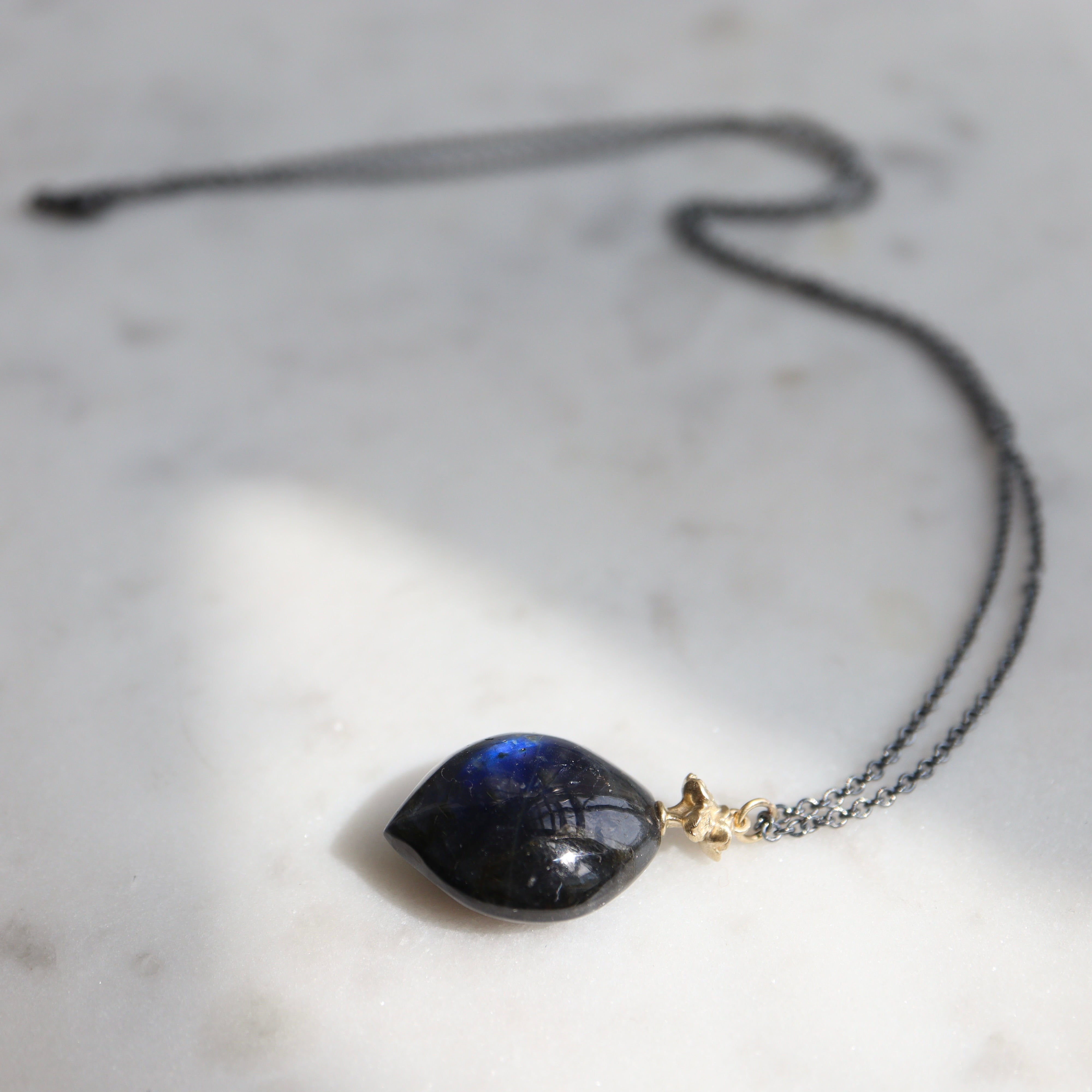 labradorite drop under a bouquet of gold flowers on an oxidized chain
