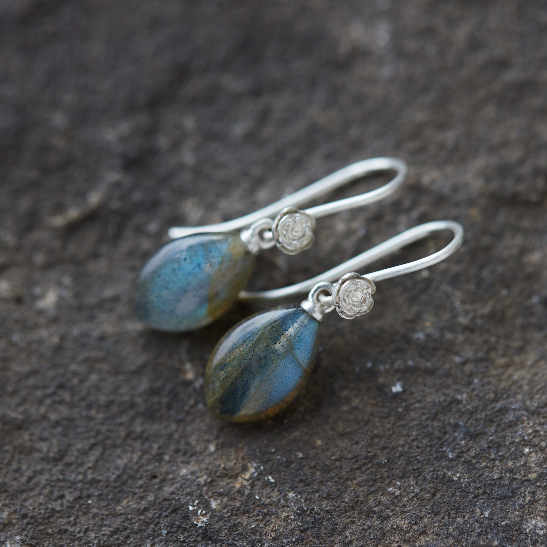 flashing with blue, grey labradorite cones hang beneath silver ear wires and silver roses. 