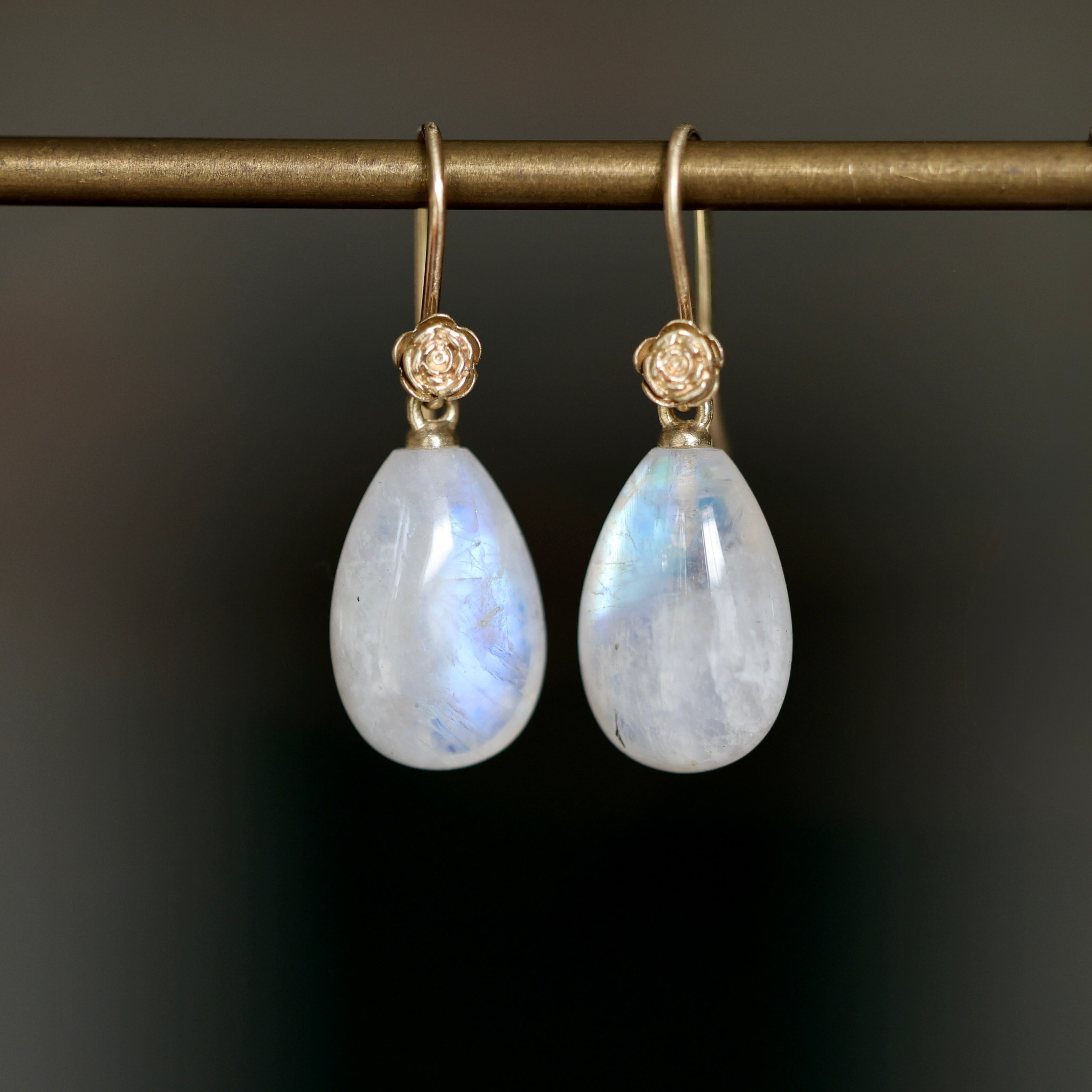 Teardrop shaped moonstone earrings with 14k yellow gold ear wires and rose accents.