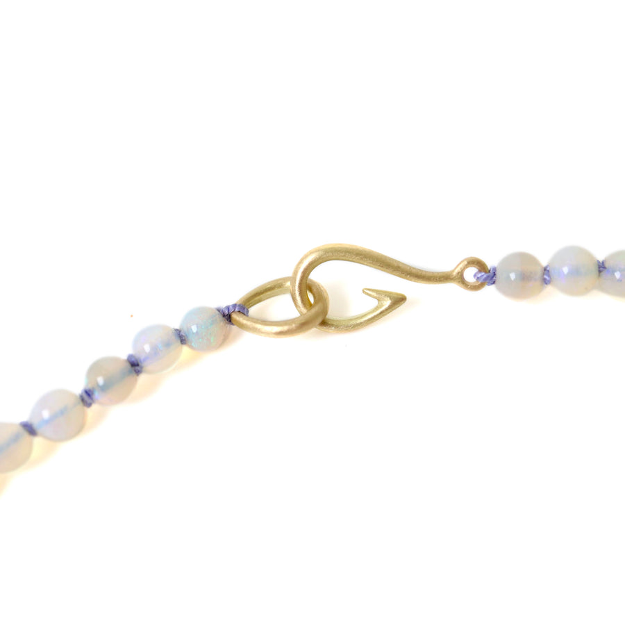 detail of string of opal bead necklace with lavender silk and gold fish hook clasp