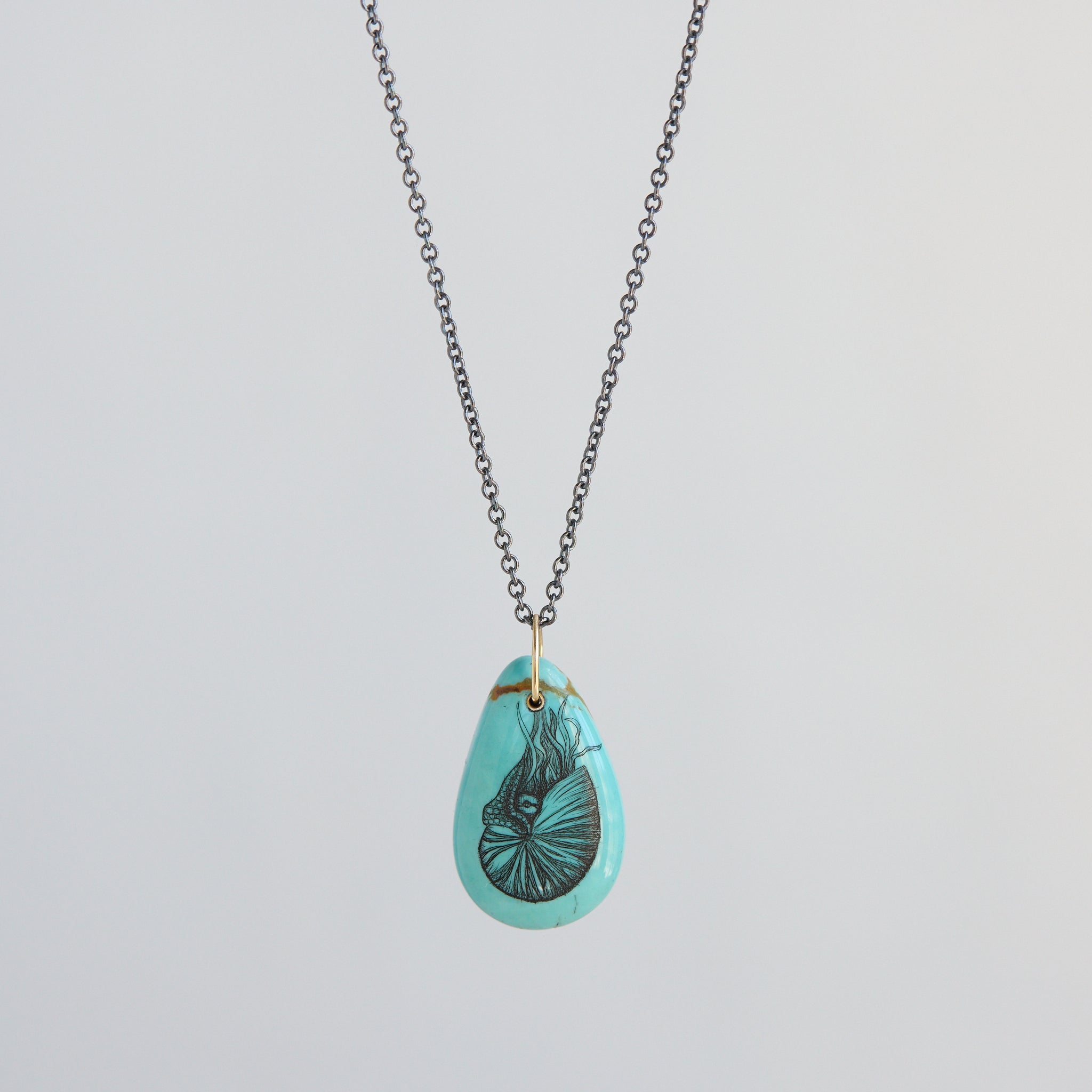 Turquoise teardrop pendant necklace with a nautilus illustration on a light gray background