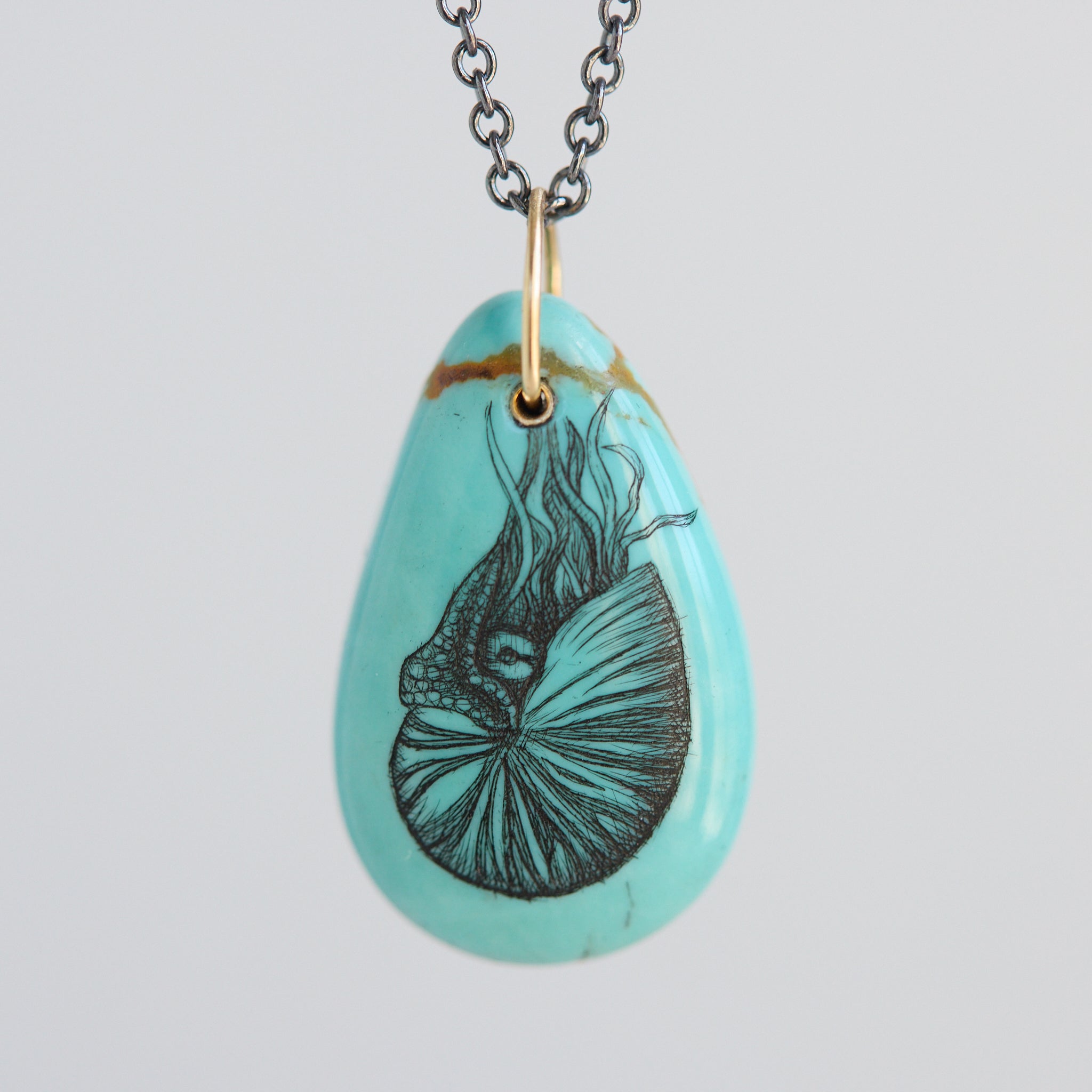 Turquoise teardrop pendant necklace with a nautilus illustration on a light gray background