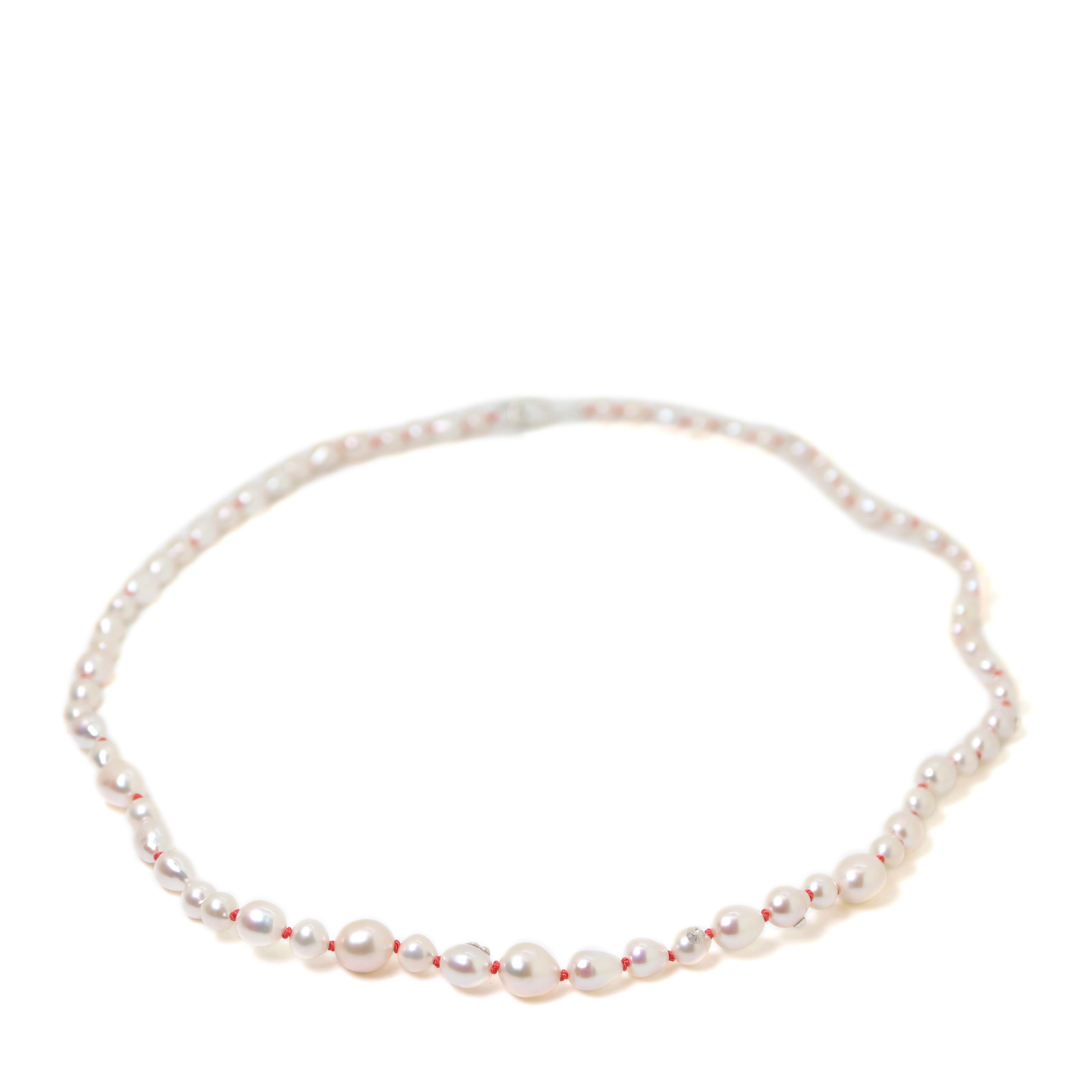 necklace made of multi sized white freshwater baroque pearls strung on coral silk with silver barnacles and fish hook clasp