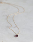Necklace with a purple gemstone pendant on a marble surface