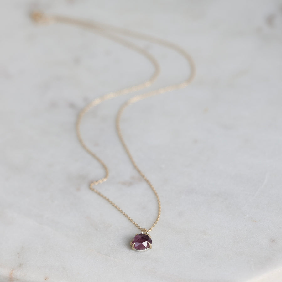Necklace with a purple gemstone pendant on a marble surface