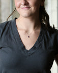 woman wearing dark grey shirt with purple pendant necklace
