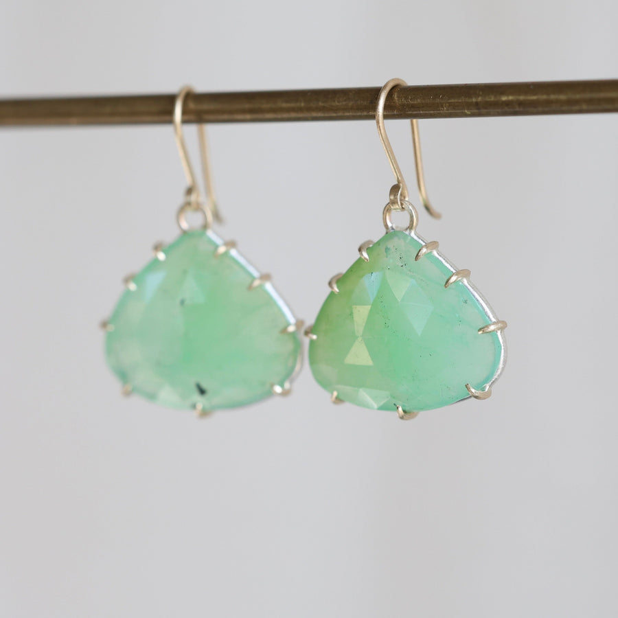 Pair of green teardrop earrings on a thin rod against a light background