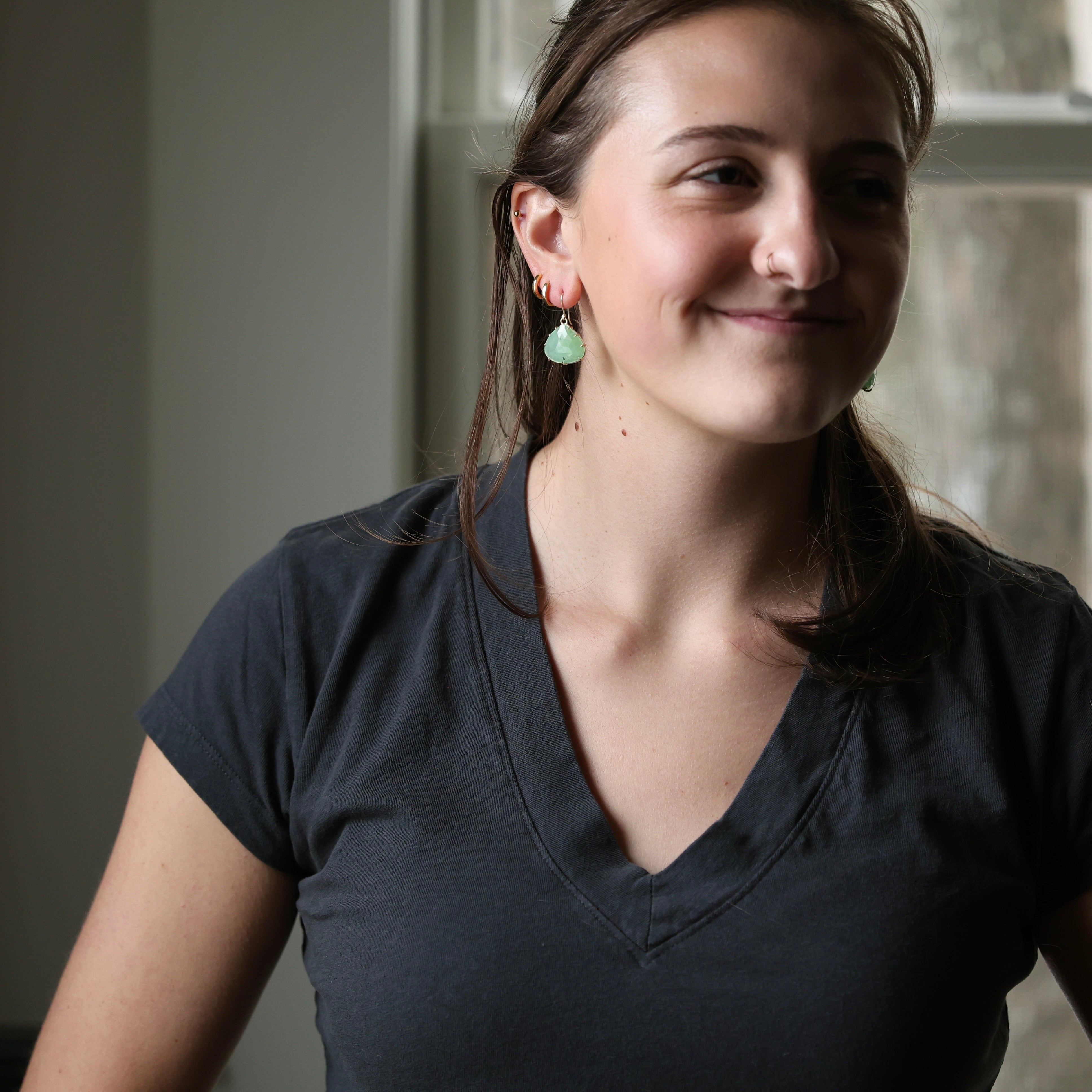 woman wearing dark grey shirt with bright green earrings