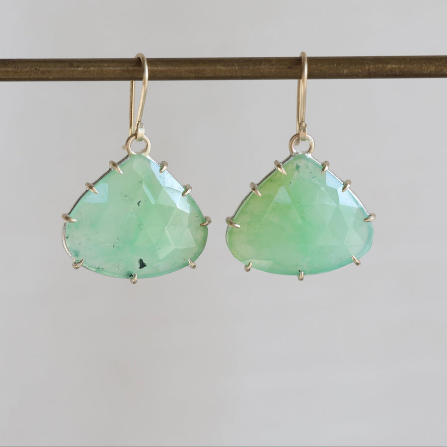 Pair of green teardrop earrings on a thin rod against a light gray background