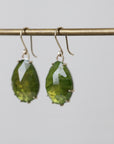 Green teardrop earrings on a gray background