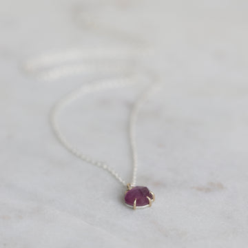 Necklace with a purple pendant on a light gray background