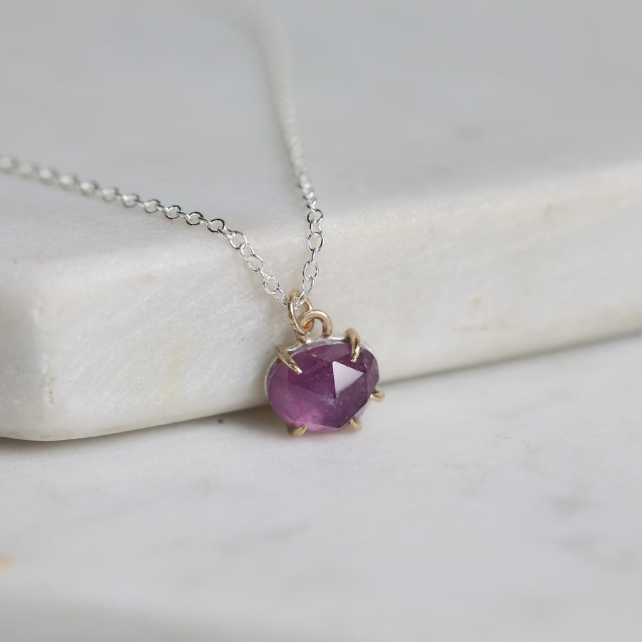 Necklace with a purple gemstone pendant on a marble surface