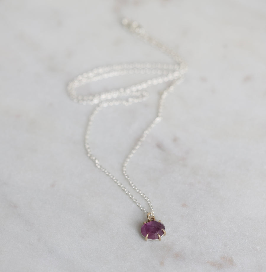 Silver necklace with a purple gemstone pendant on a light gray background