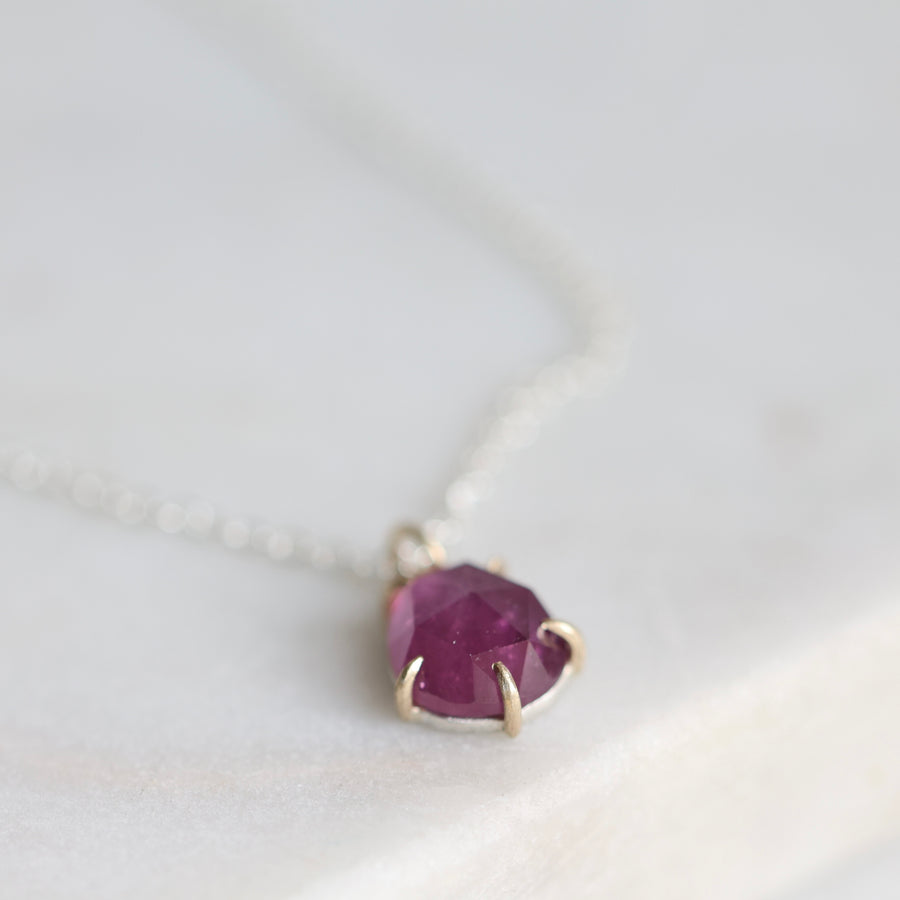 Necklace with a drop-shaped purple gemstone on a white background