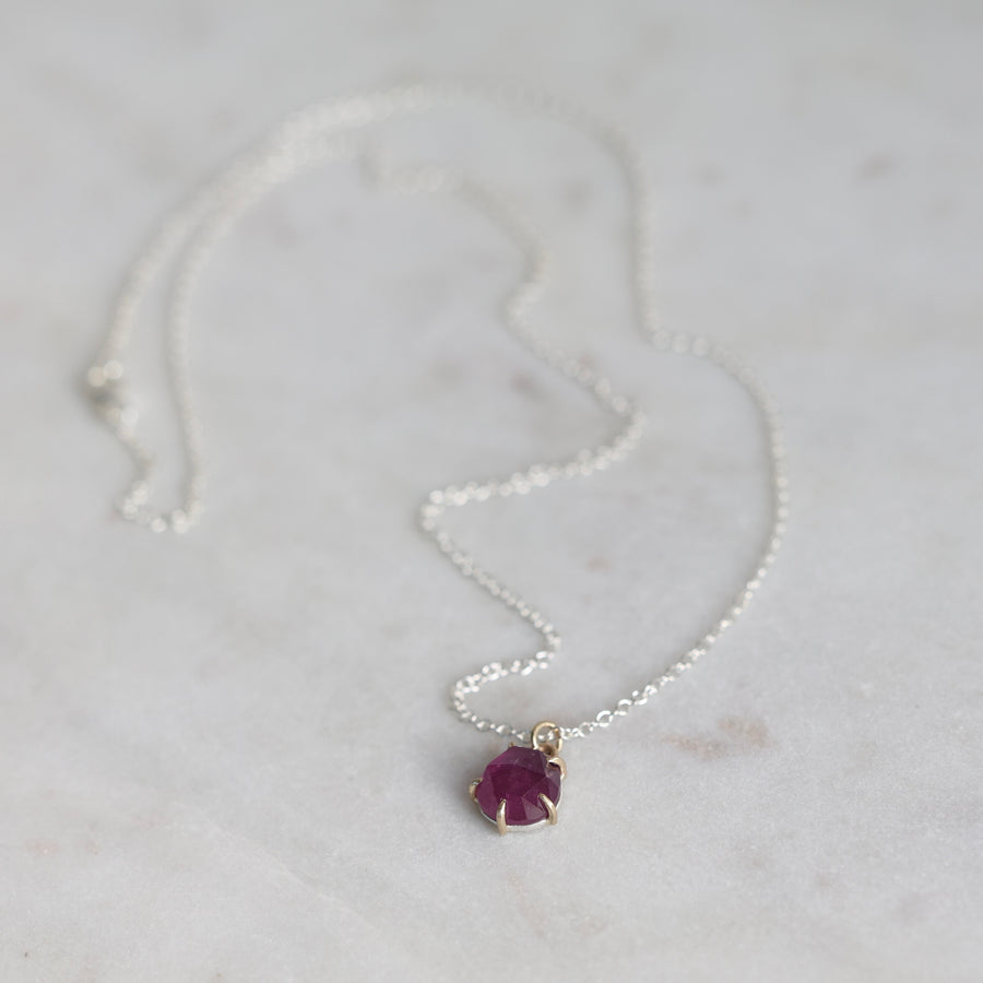 Silver necklace with a purple gemstone pendant on a light gray background