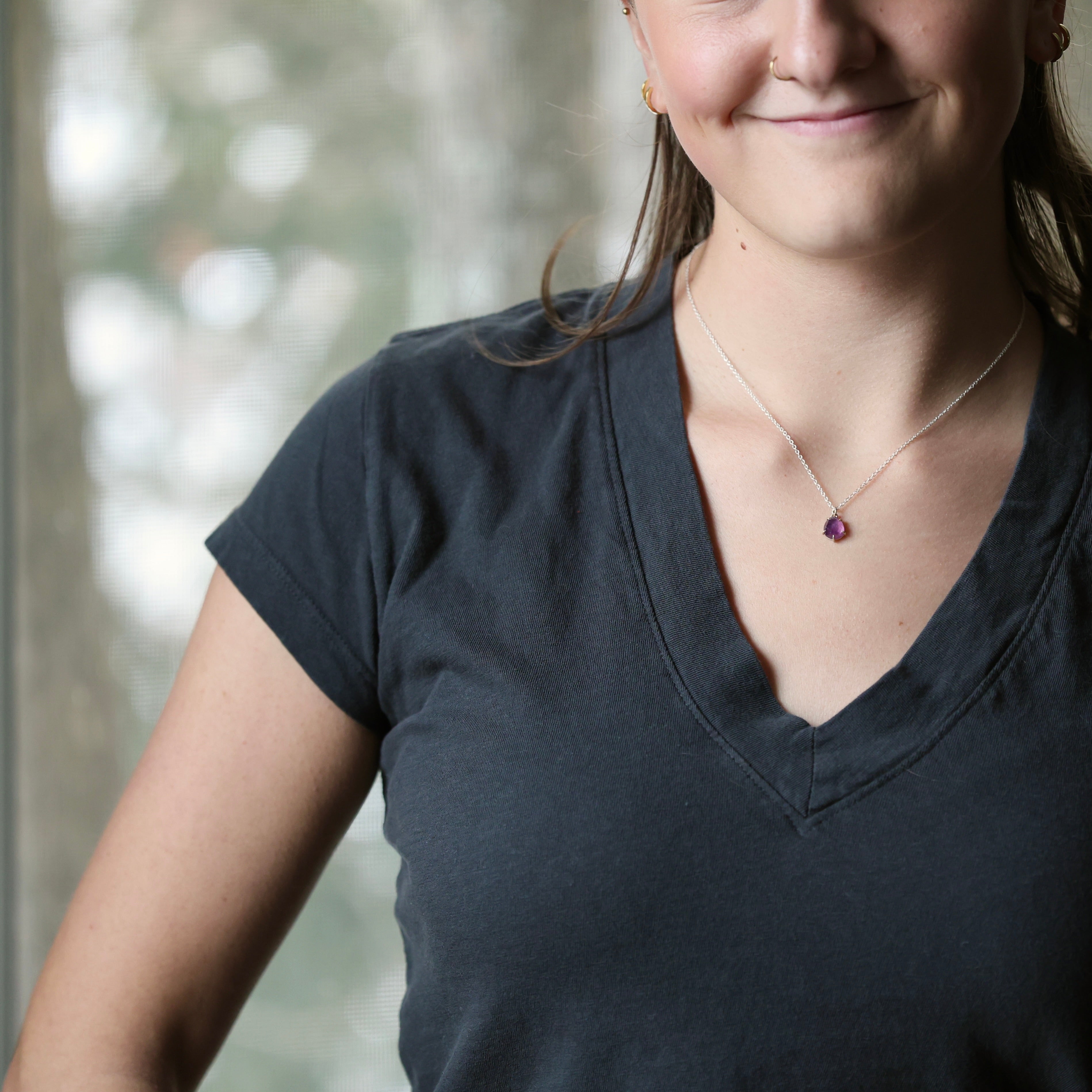 dark grey shirt with purple pendant necklace