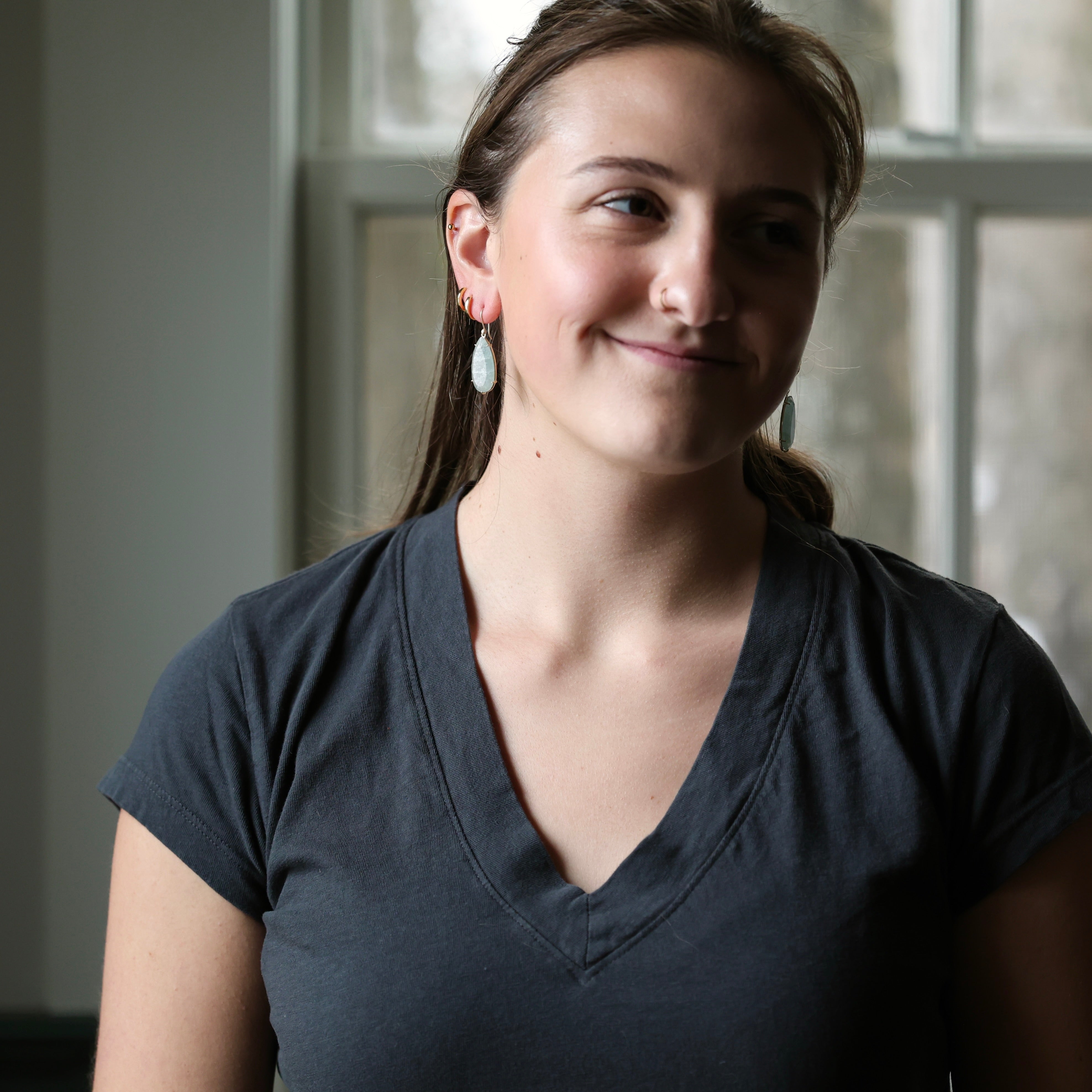 woman with dark grey shirt and light blue earrings