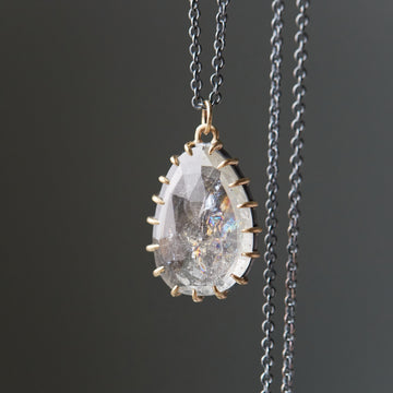 detail of clear tourmaline pendant necklace with gold prongs