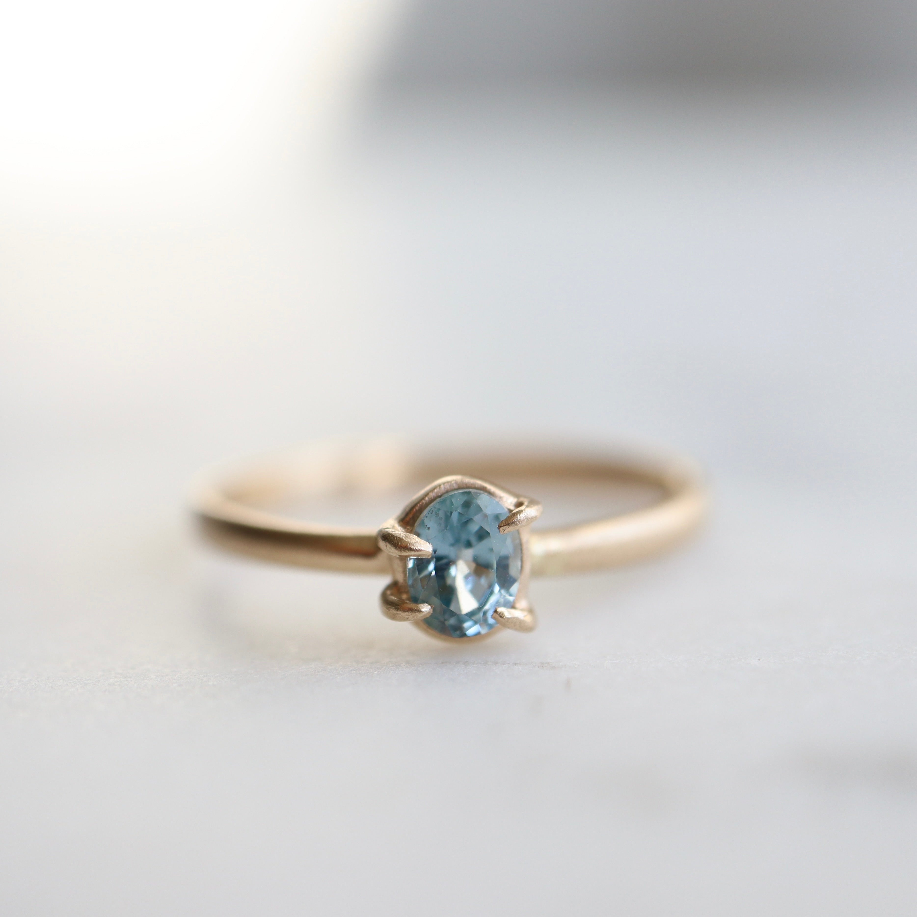 0.4ct pale blue Montana sapphire vanity ring set in 14k yellow gold with four asymmetrical prongs.