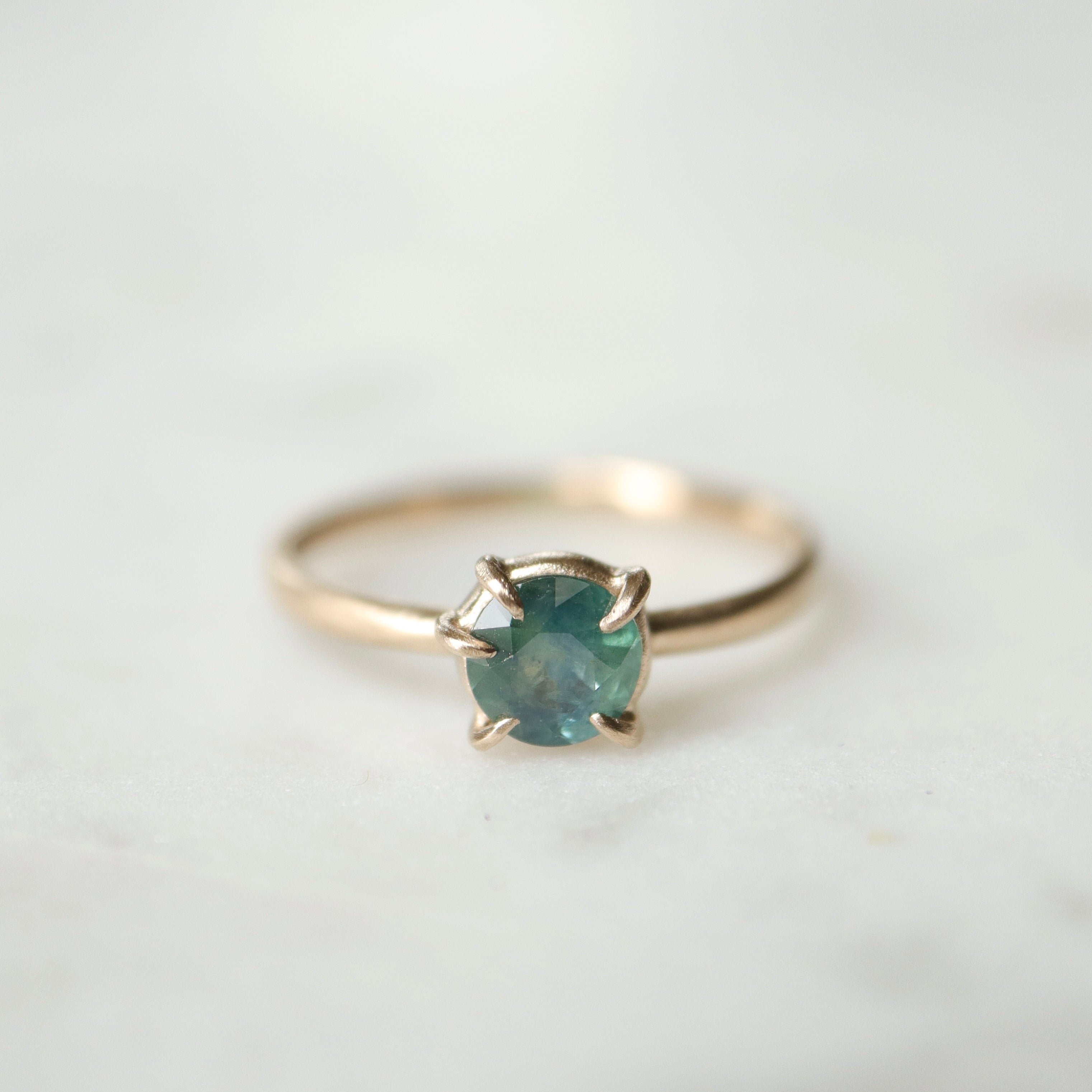 teal montana sapphire set in gold prongs on a gold ring