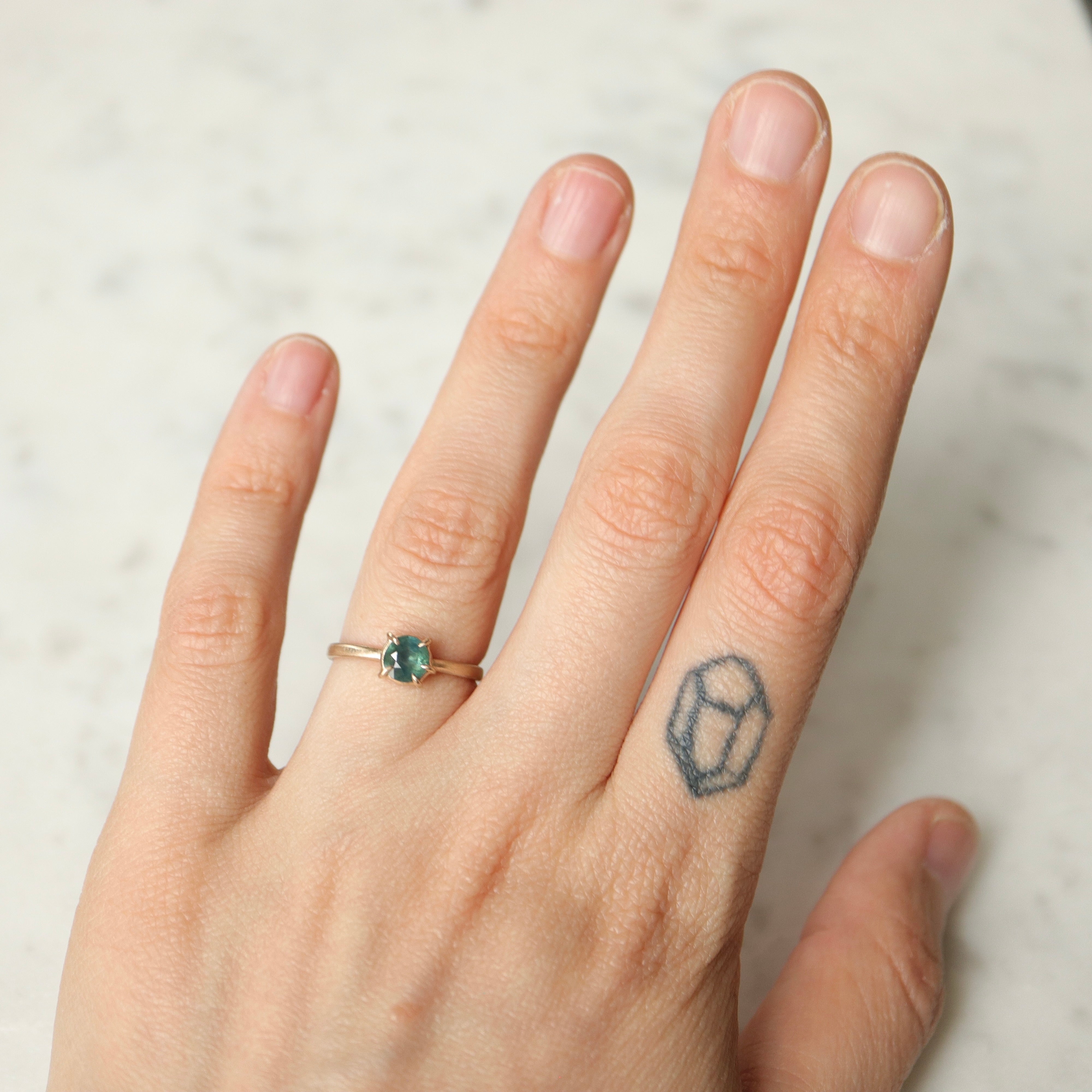 teal montana sapphire set in gold prongs on a gold ring- on hand