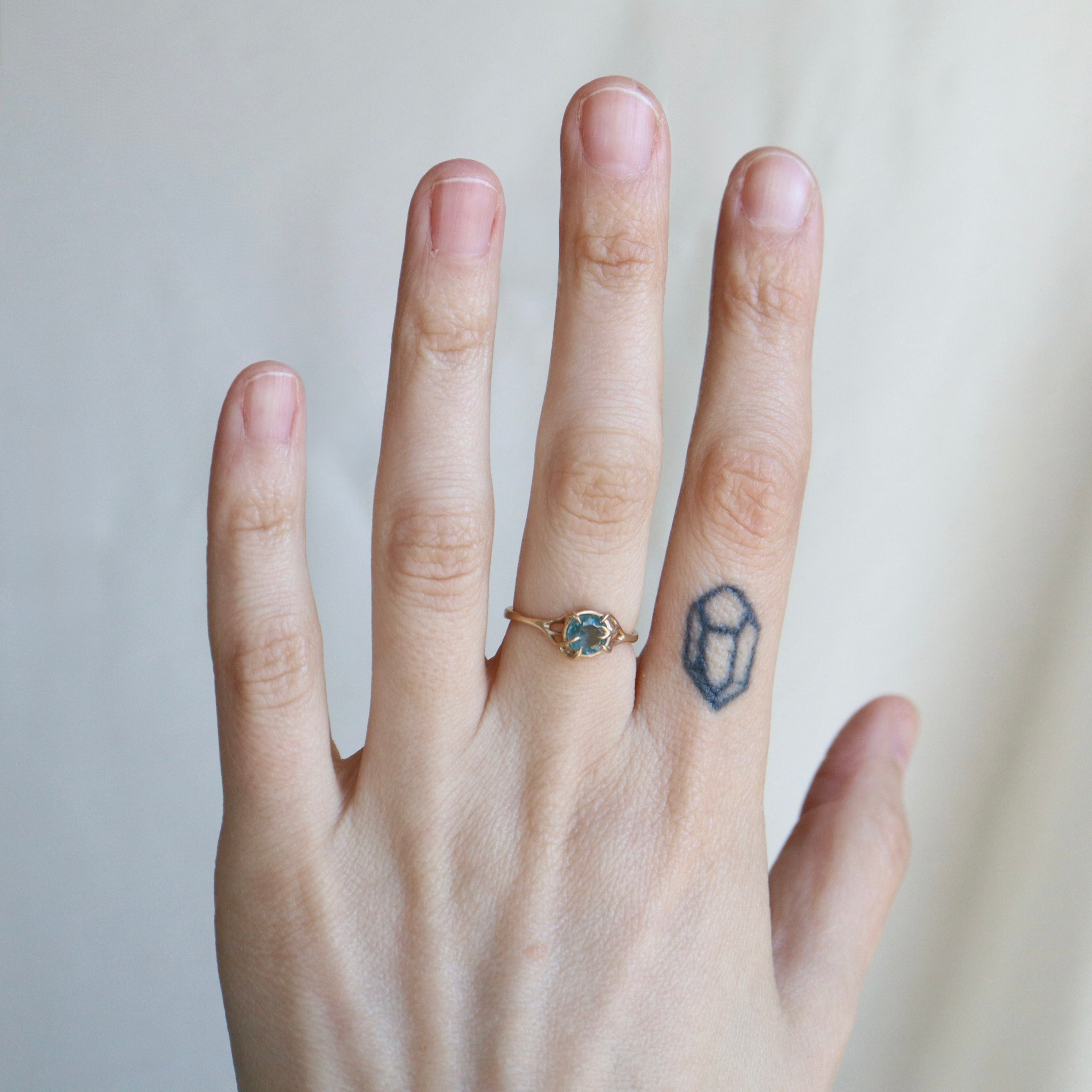 Hand with a ring and a small tattoo on a plain background