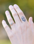 Hand with a ring and a small tattoo on a blurred natural background