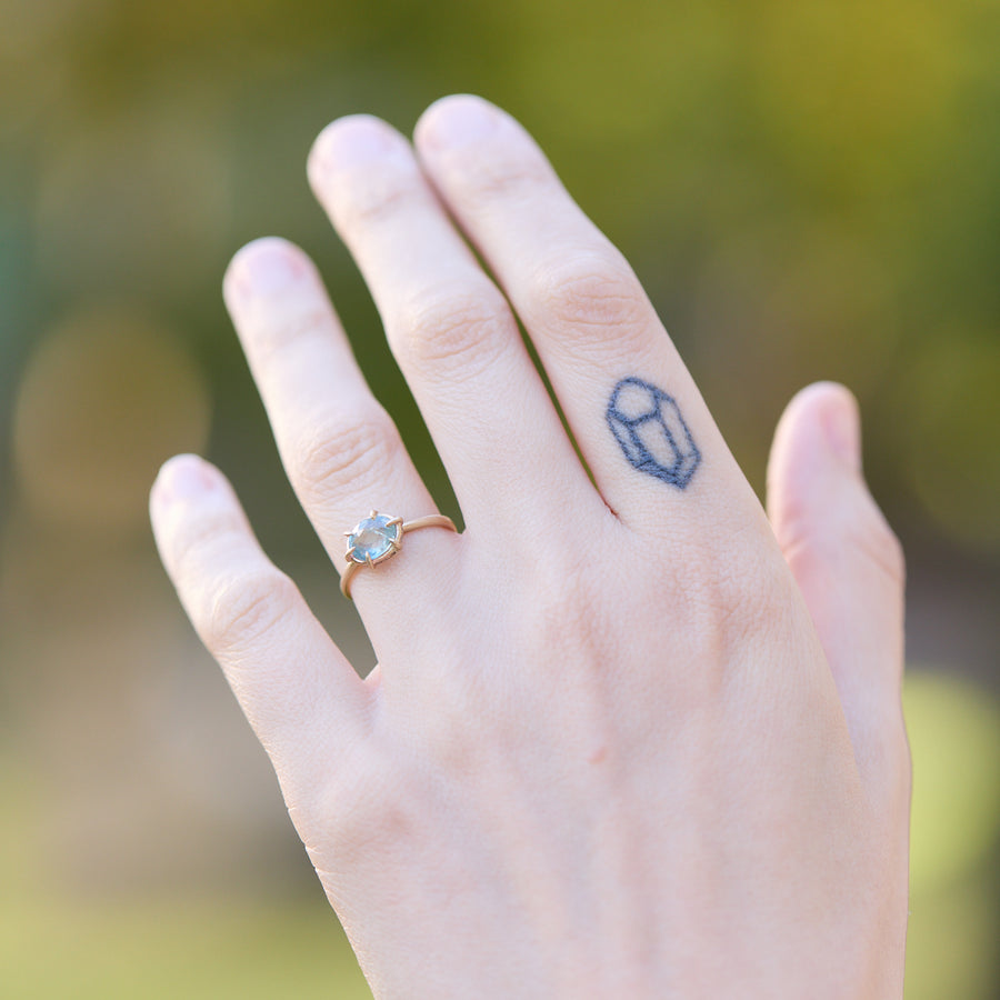 Hand with a ring and a small tattoo on a blurred natural background