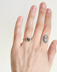 Hand wearing a ring with a gemstone on a plain background