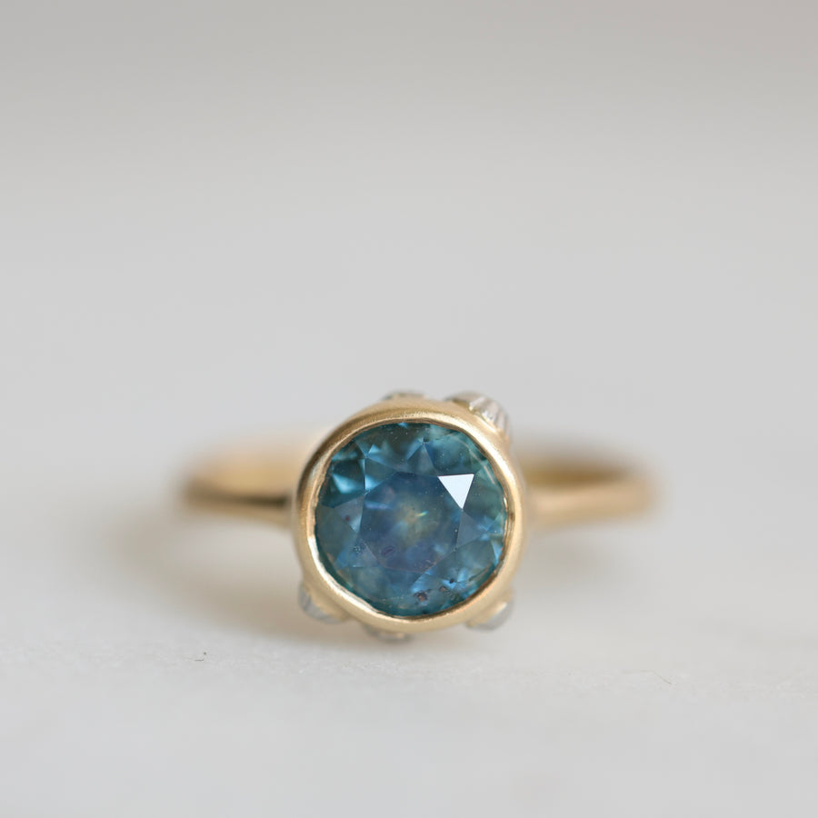 Gold ring with a blue gemstone on a light gray background