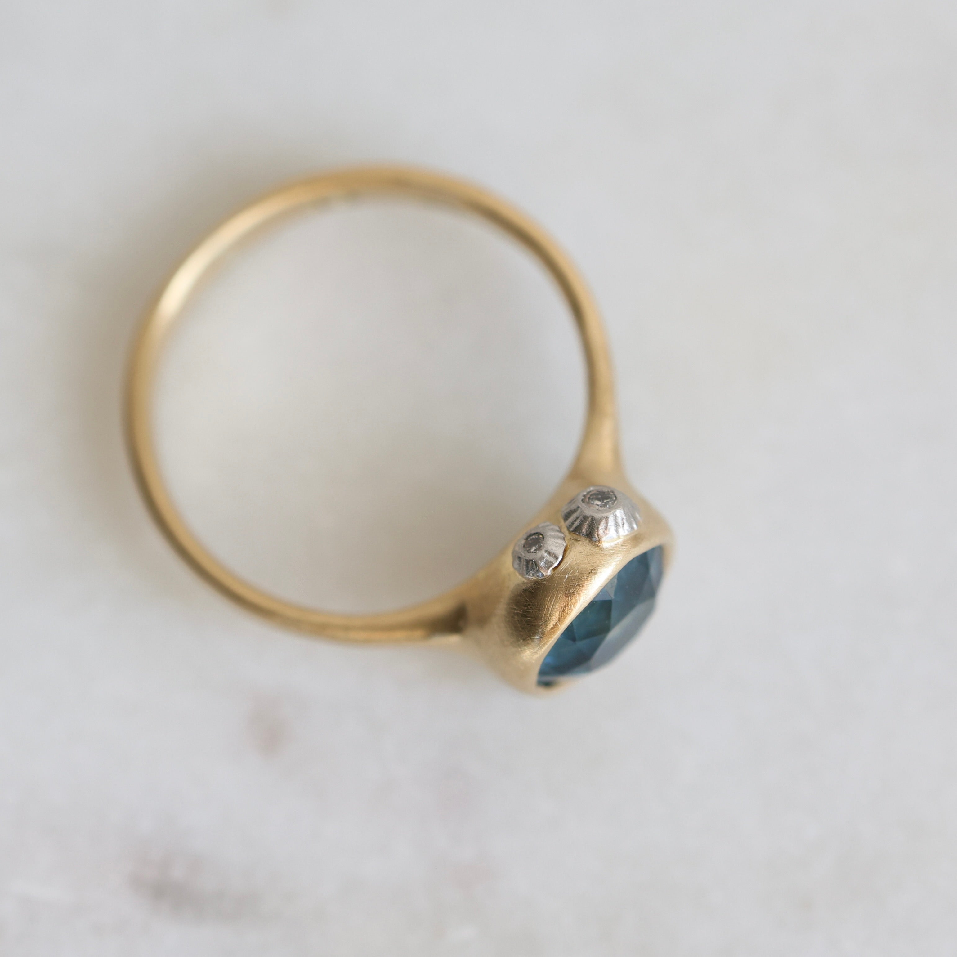 Gold ring with a blue gemstone on a light gray background