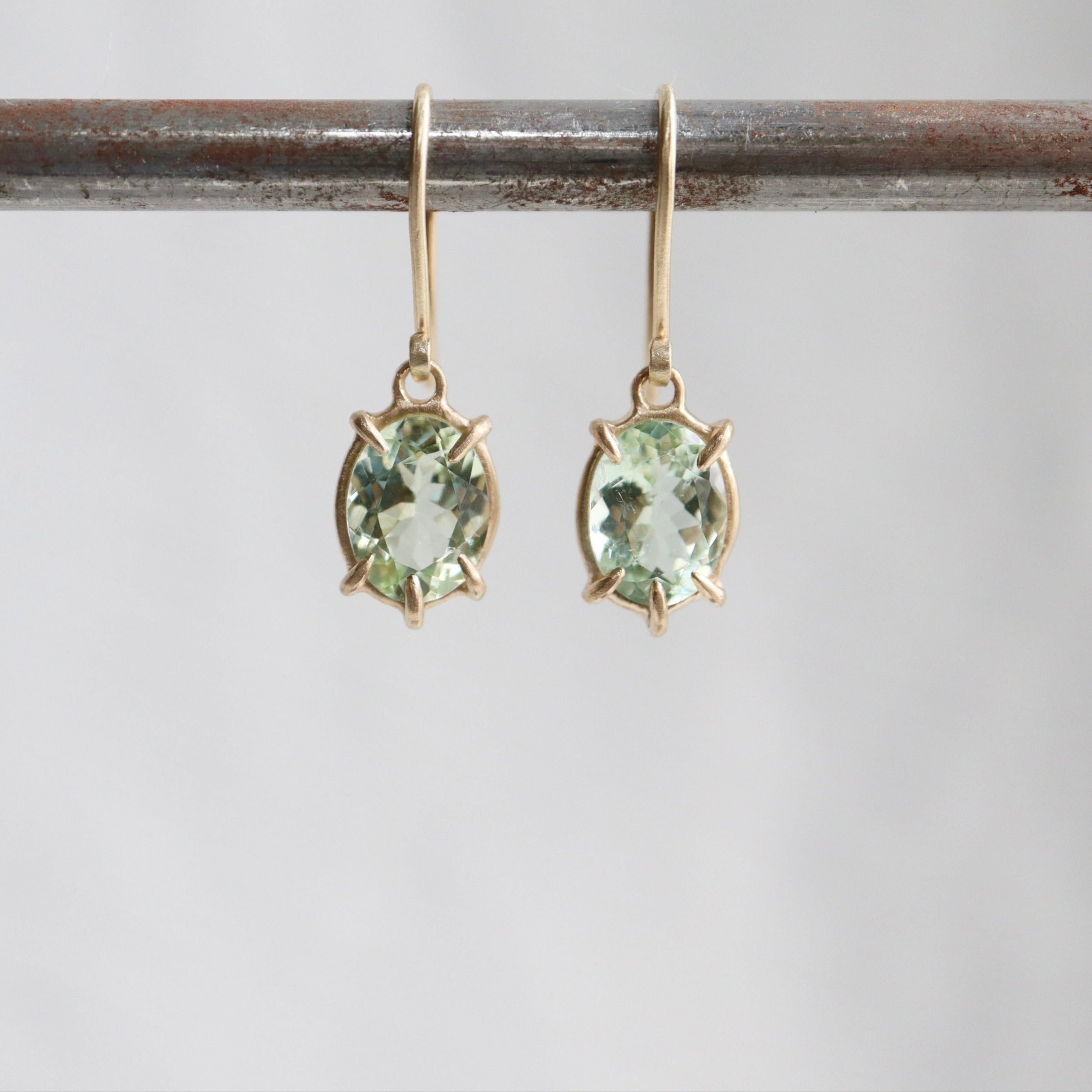 gold prong earrings featuring pale green tourmaline oval gemstones
