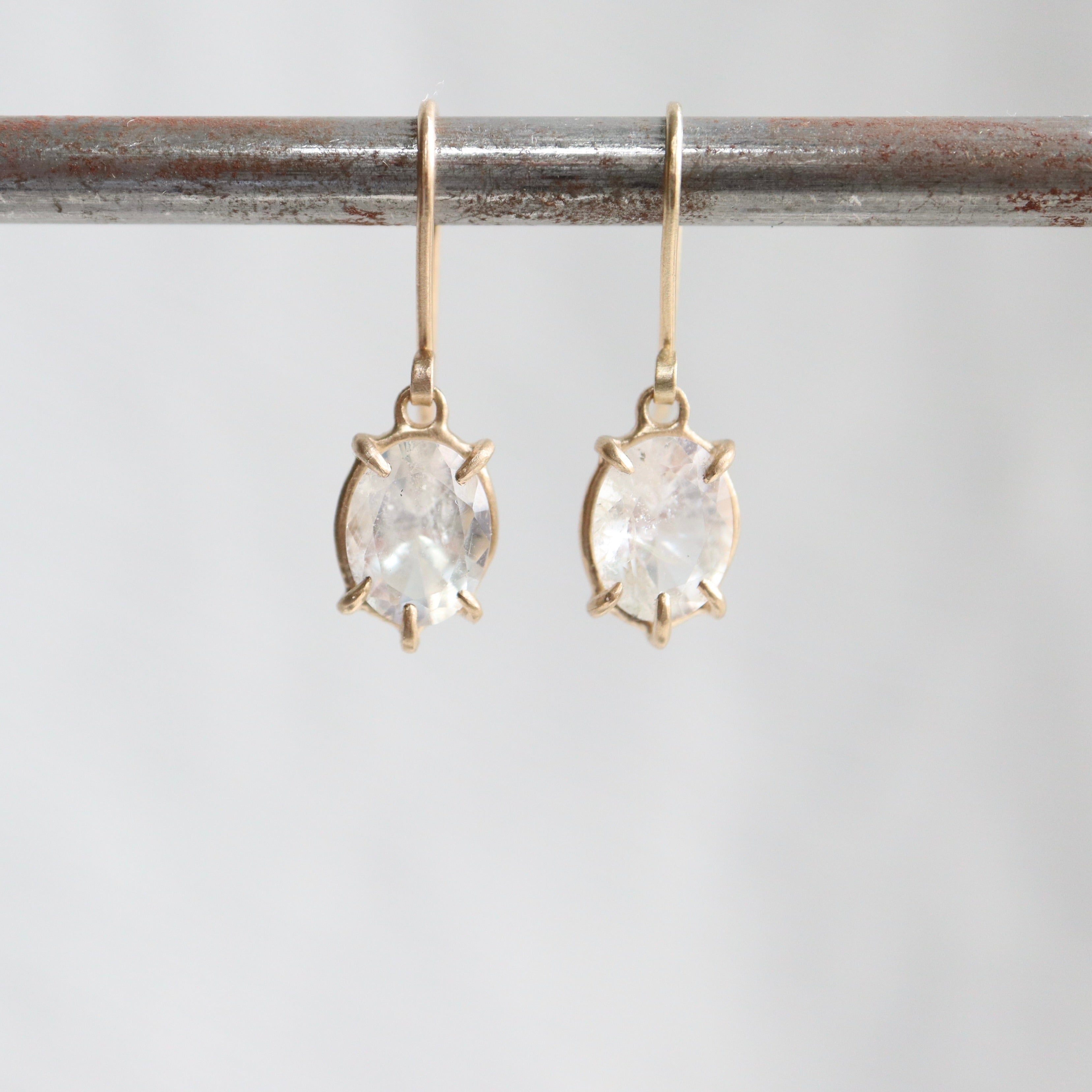 a pair of earrings features oval rainbow moonstones set in gold prongs