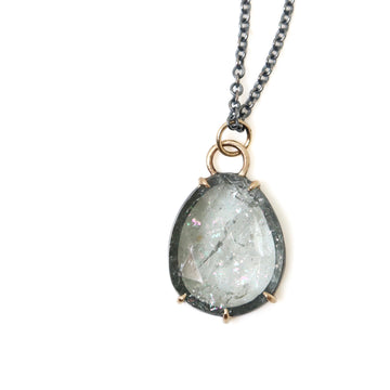 detail of green grey tourmaline pendant necklace with gold prongs