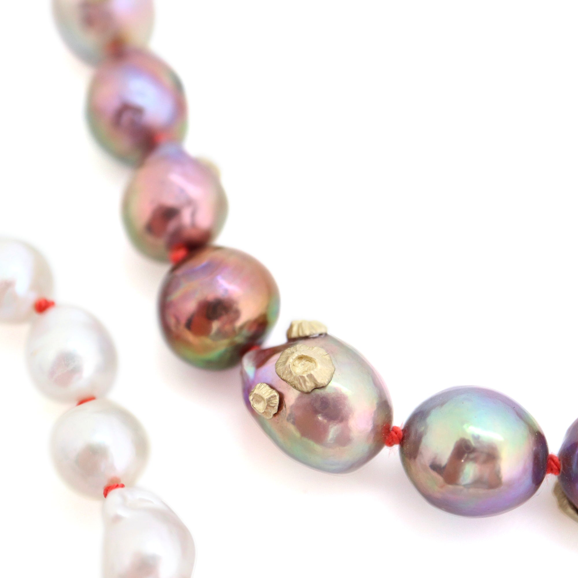 detail of pink and white freshwater baroque pearl necklace in ombre pattern with gold barnacles and fish hook clasp and coral silk by hannah blount jewelry