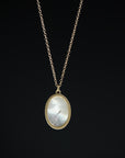 Necklace with a gold chain and oval pendant on a black background