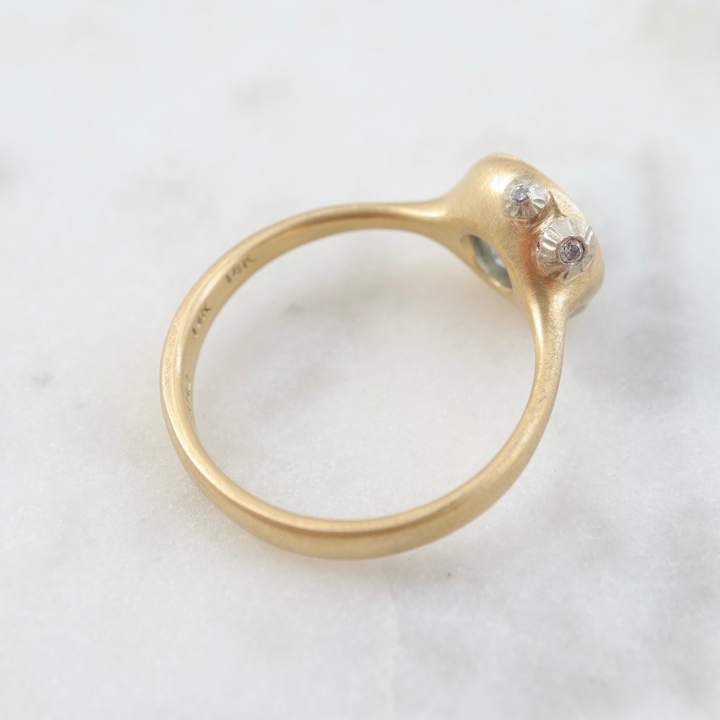 periwinkle sapphire set in a yellow gold ring with three white gold barnacles with diamonds. Back view.