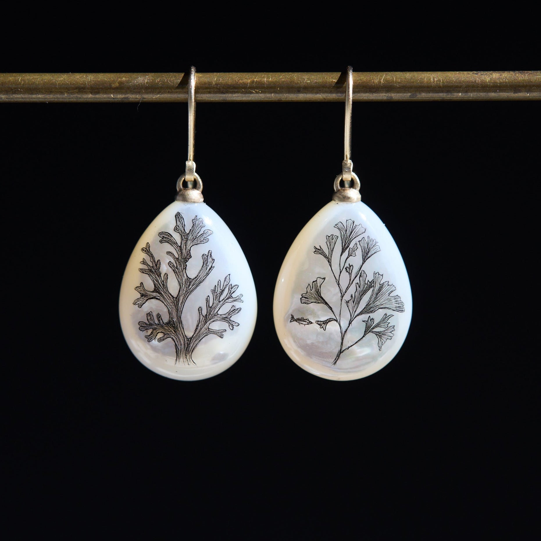 Teardrop-shaped earrings with seaweed pattern on a black background