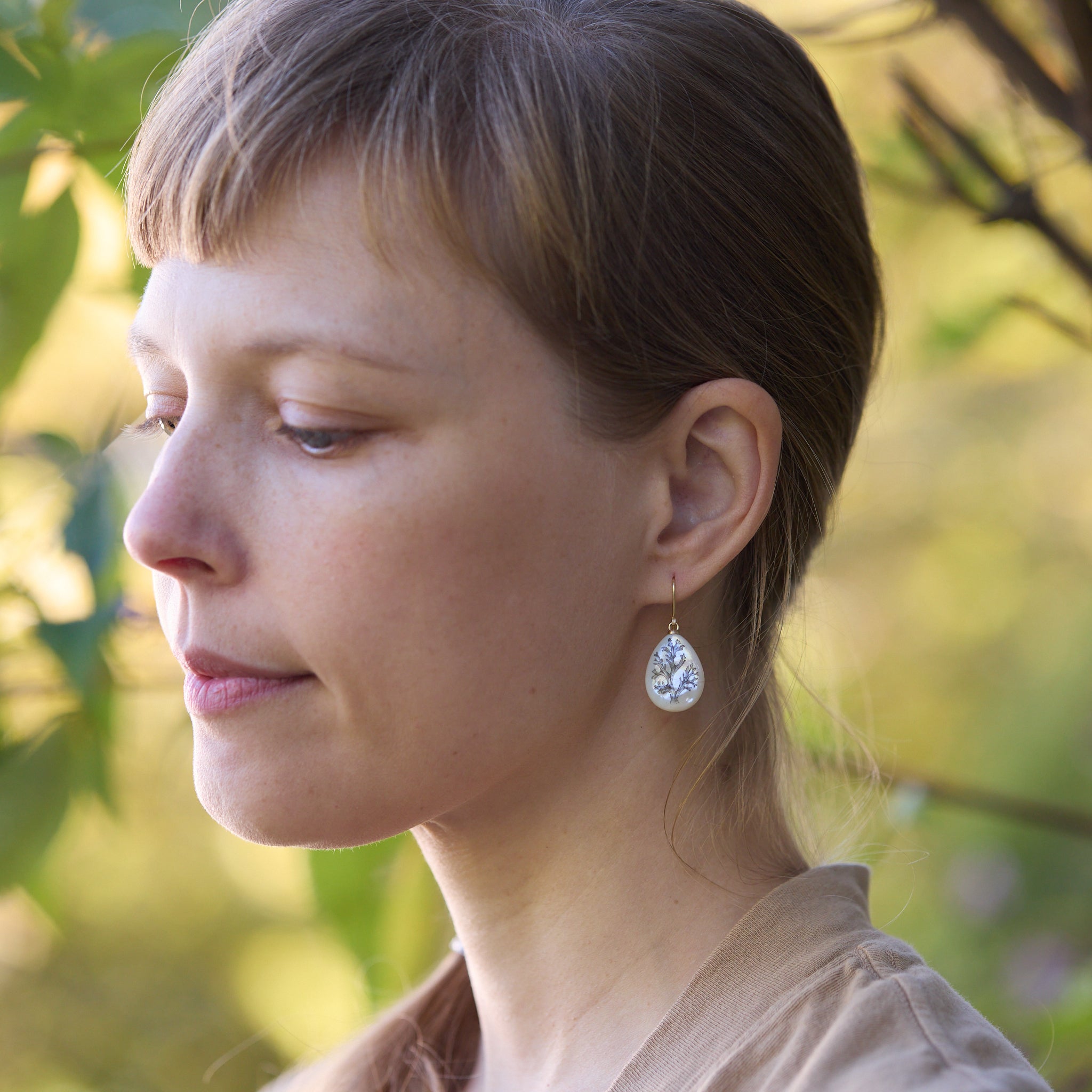 Woman wearing earrings with a blurred natural background