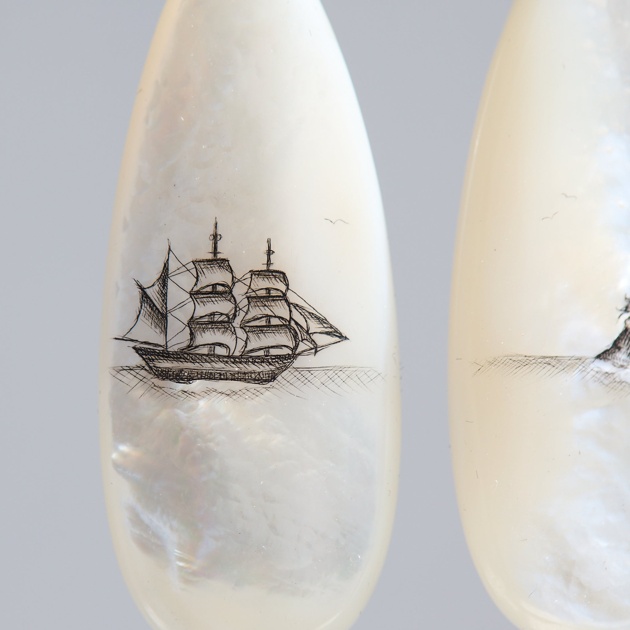 Teardrop-shaped mismatched earrings, a ship design on one and a mermaid on the other. 