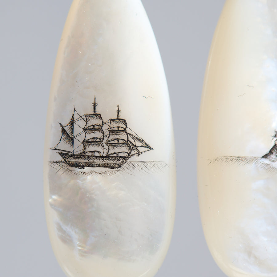 Teardrop-shaped mismatched earrings, a ship design on one and a mermaid on the other. 