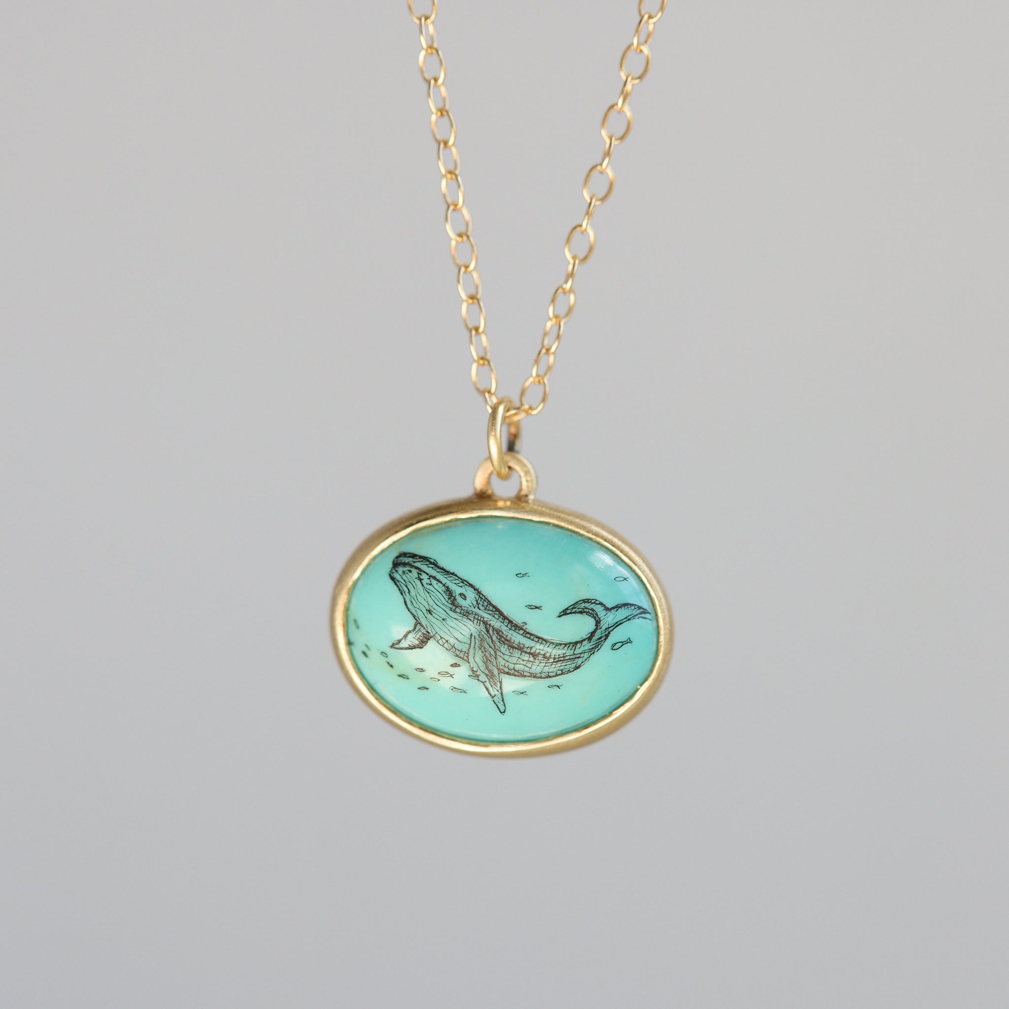 Necklace with a pendant featuring a whale design on a gray background