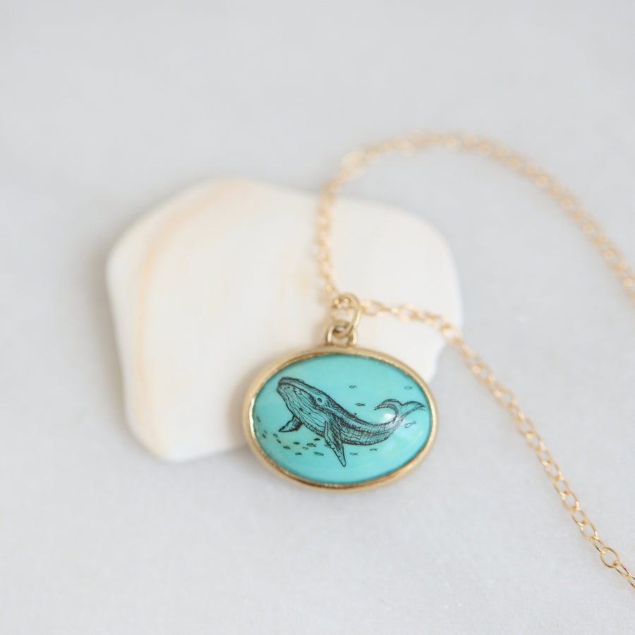 Necklace with a turquoise pendant featuring a whale design on a light gray background