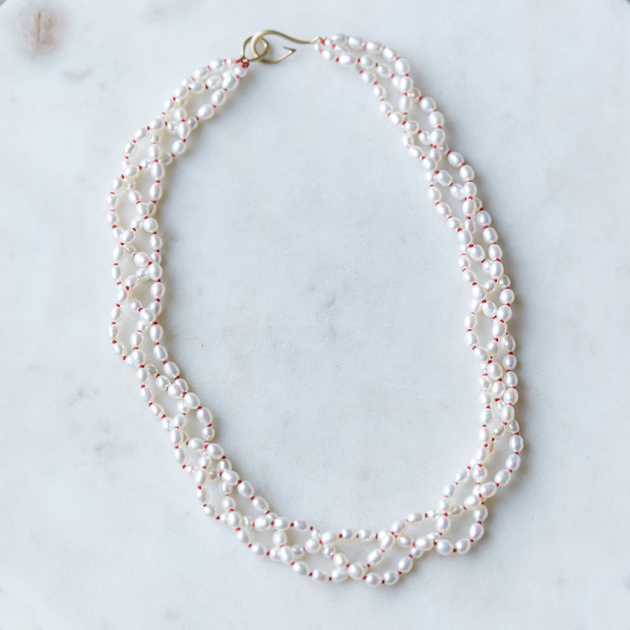 Three strands of white freshwater pearls with coral-hued silk braided together - Hannah Blount