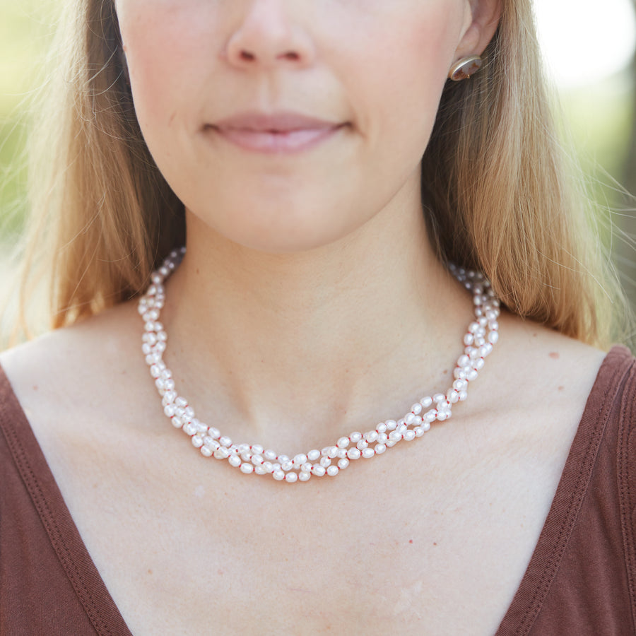 Three strands of white freshwater pearls with coral-hued silk braided together - Hannah Blount