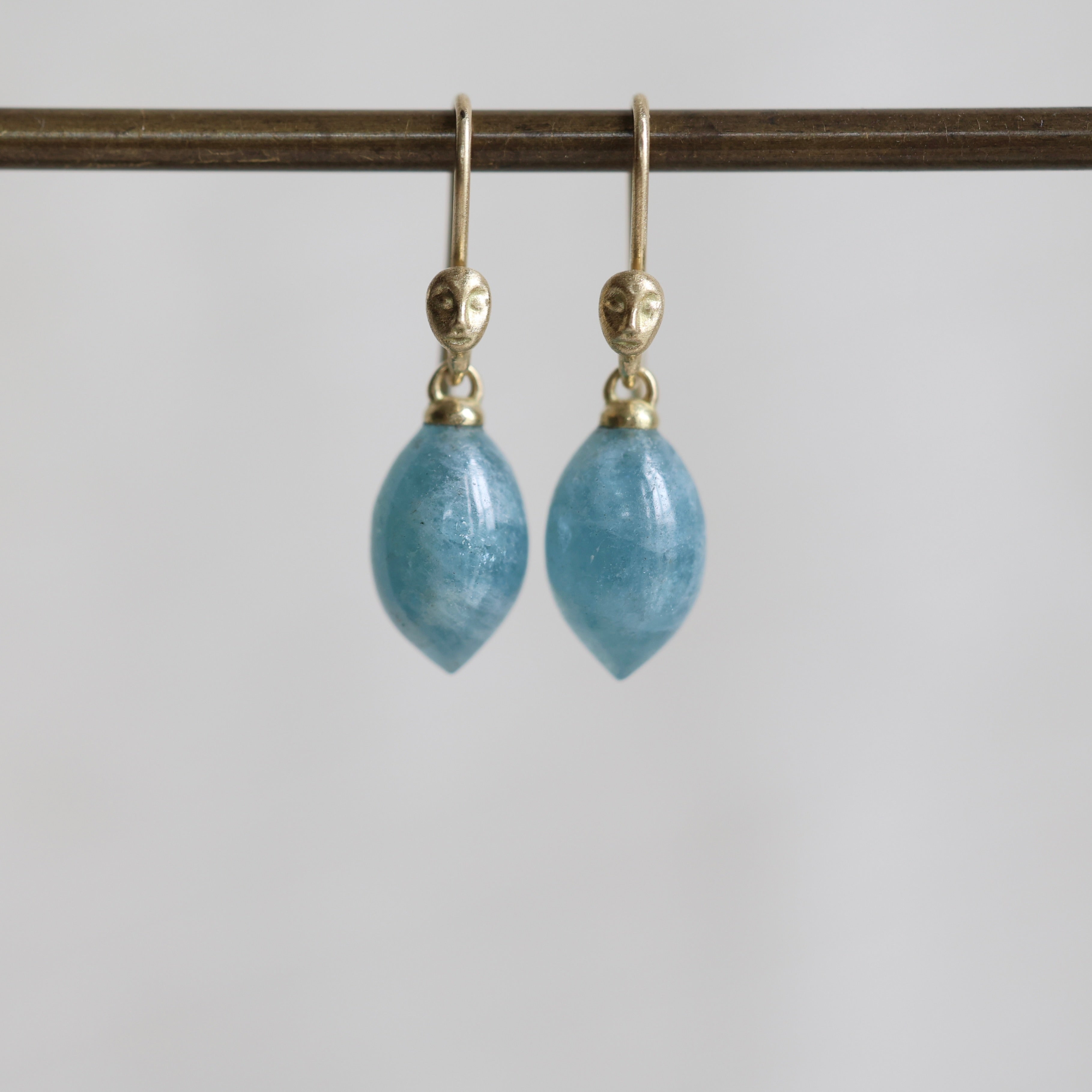 Pair of blue teardrop earrings with gold hooks on a white background