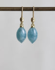 Pair of blue teardrop earrings with gold hooks on a white background