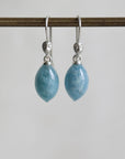 Pair of blue teardrop earrings with silver hooks on a white background