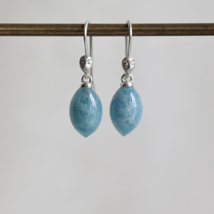 Pair of blue teardrop earrings with silver hooks on a white background