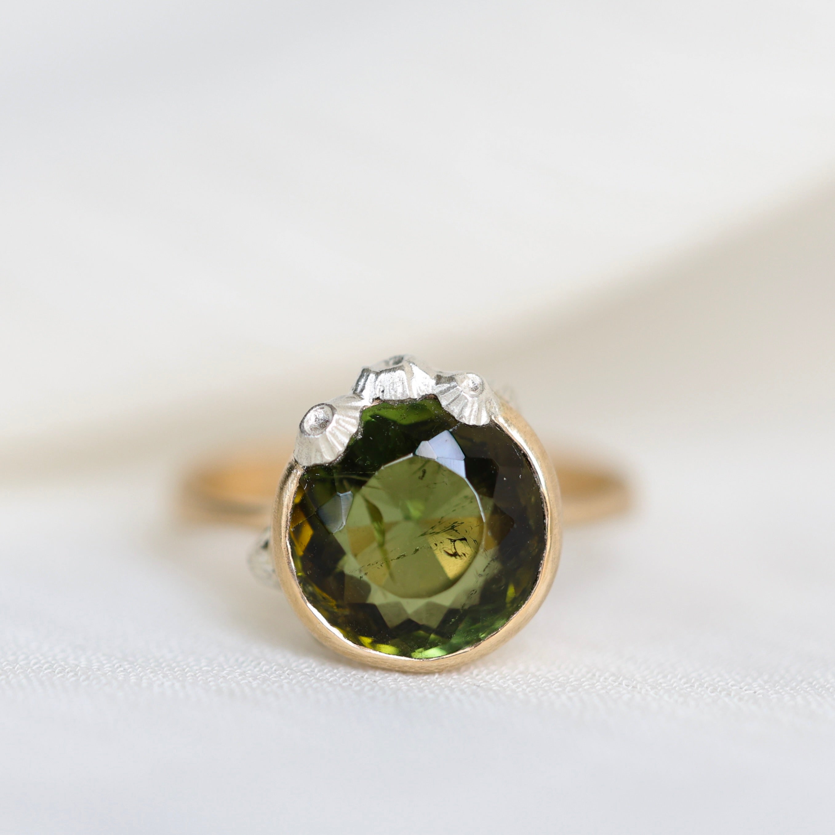 Ring with a green gemstone and gold band on a white background